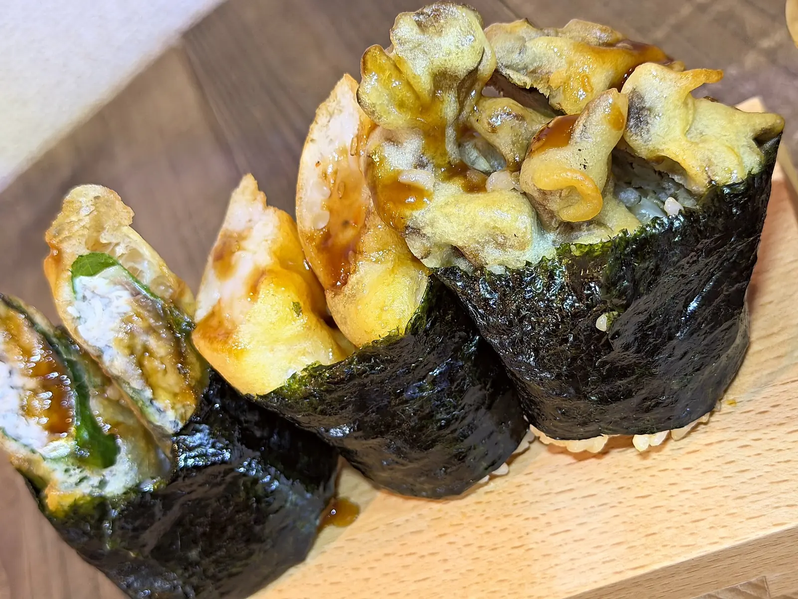 下駄に並んだ天むす3巻。海苔で巻いたご飯に、タレをからめた天ぷらがのる