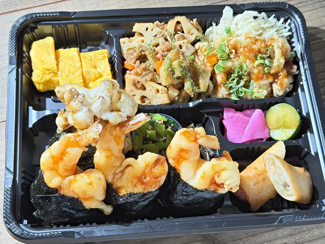 仕切りのあるお弁当箱に、大海老天むす3つと玉子焼きなどのおかず