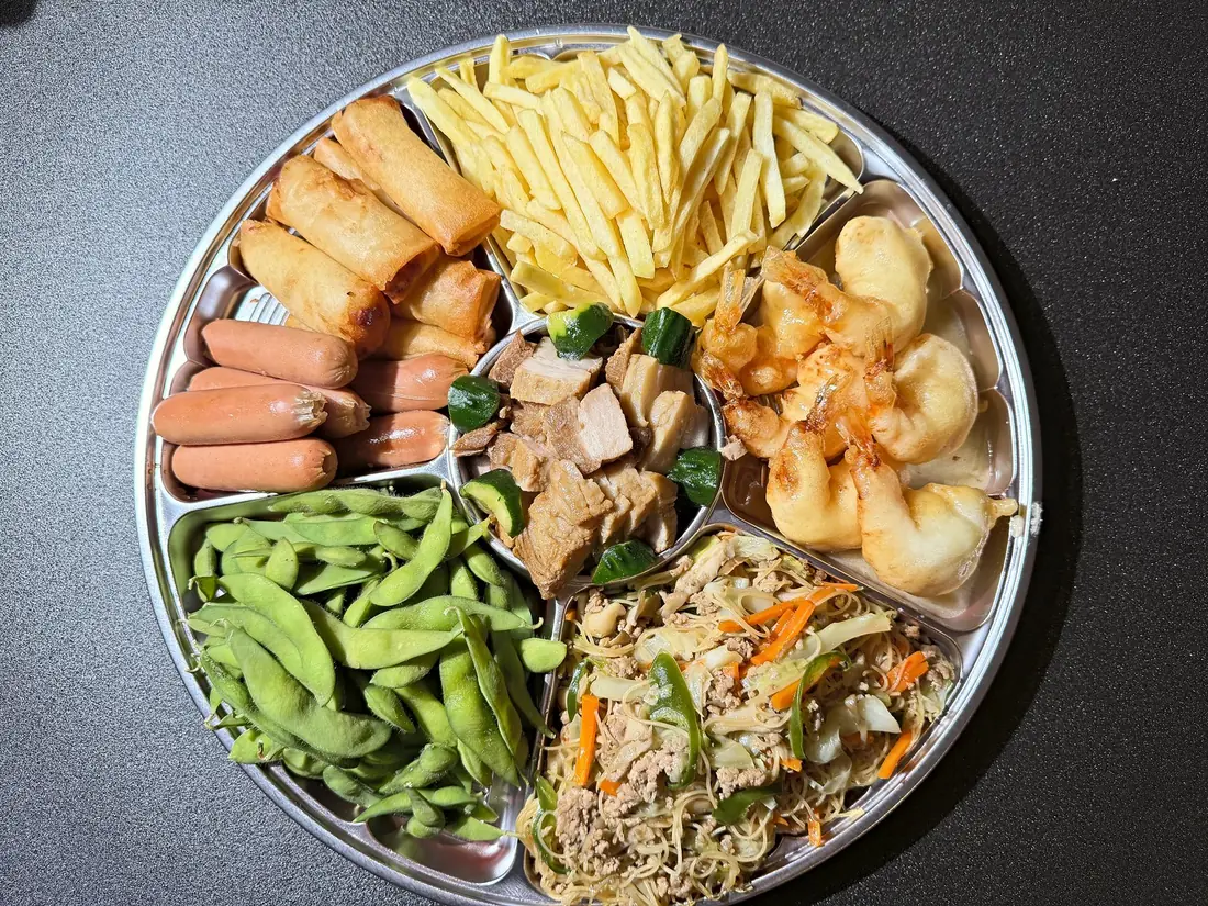 仕切りのある丸い大皿に盛ったオードブル。揚げもの、煮もの、焼きビーフン、枝豆など
